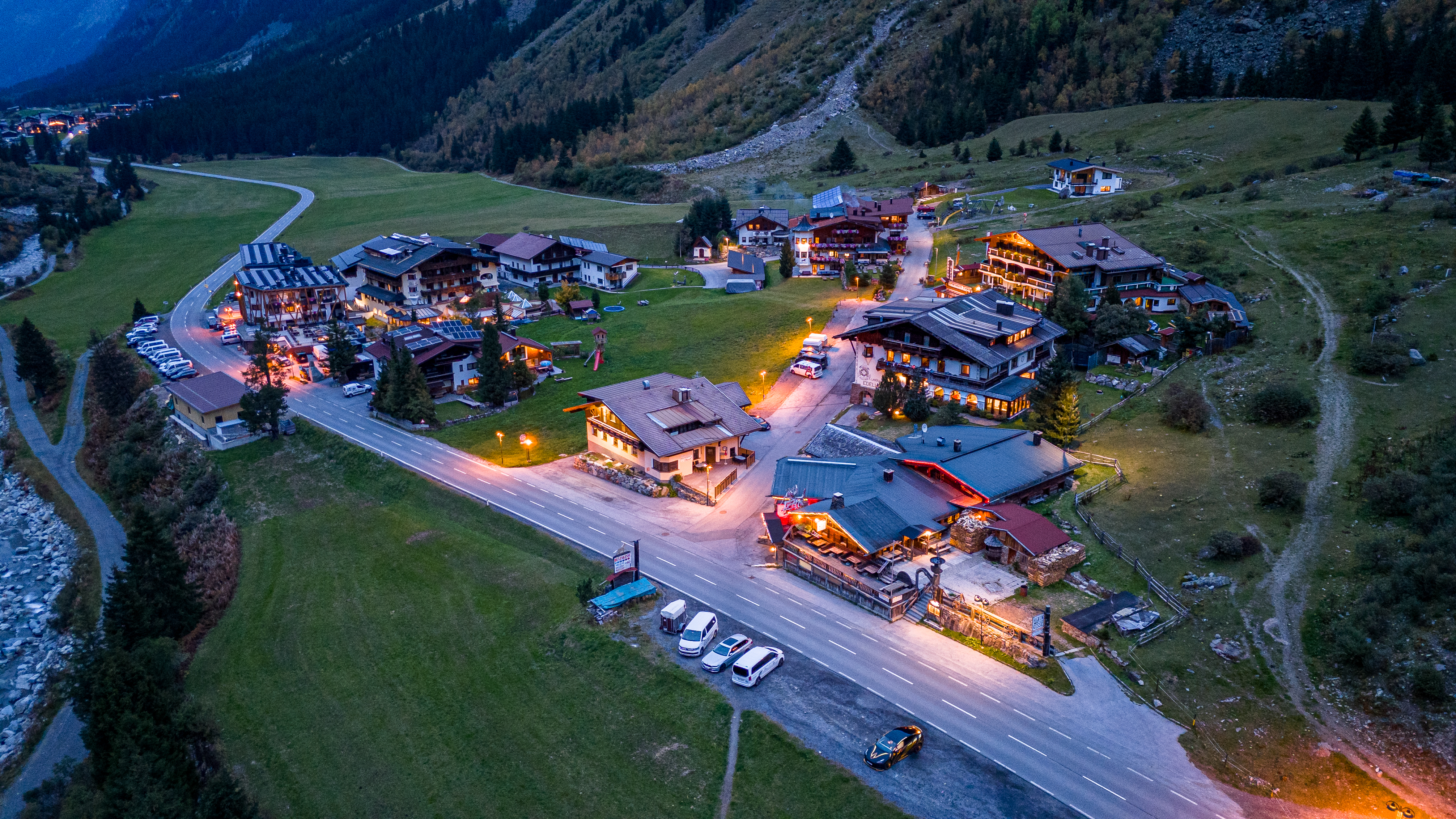 Drohnenaufnahme eines beleuchteten Bergdorfes am Abend